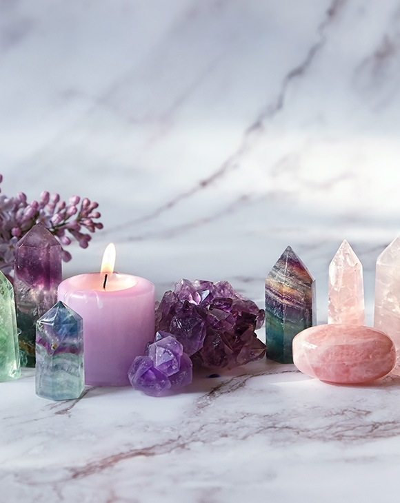 various crystals and stones including a pink candle on a marble surface peaceful energy healing with six prominent crystals