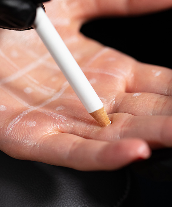a hand with a white pencil drawing on the palm creating five distinct patterns in a creative art activity